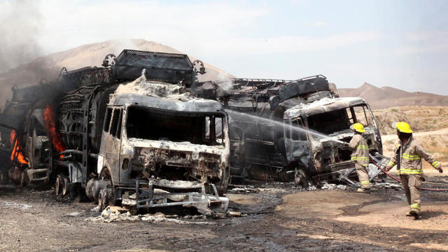 Afghan firefighters spray water on burning NATO supply trucks in Samangan, Afghanistan, July 18, 2012. 