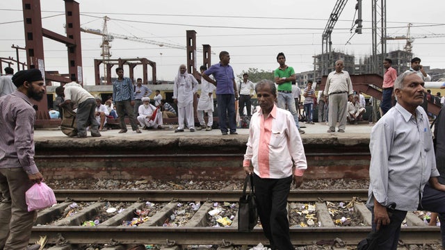 Stranded passengers stand near empty railway tracks as they wait for train services to resume 