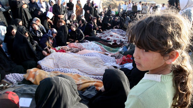 An Iranian girl mourns over the covered bodies of loved ones in Bajebaj village 