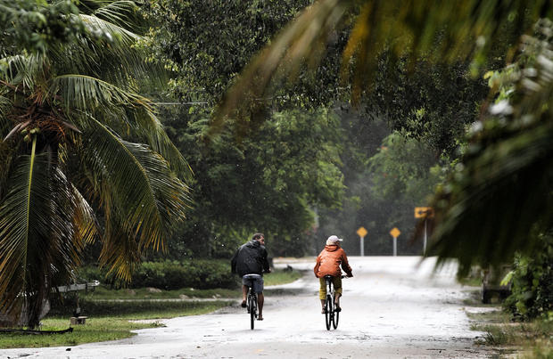 People ride bikes as as Tropical Storm Isaac begins to move ashore 