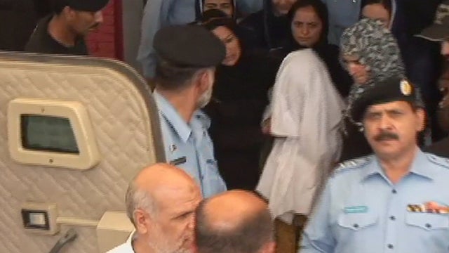 A Christian Pakistani girl, covered in a white cloth, is ushered into a police vehicle 