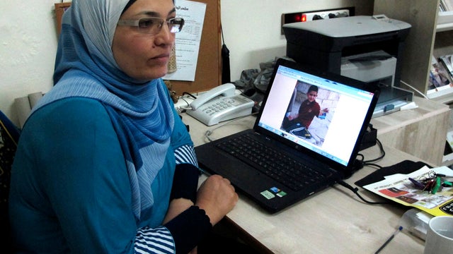 Hekmat Besesso sits beside a laptop that shows an image of her son 