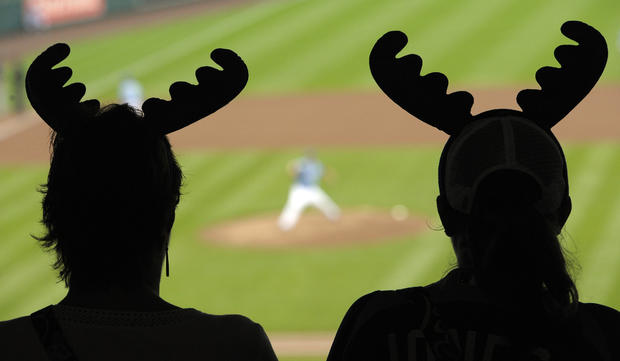 A pair of fans watch the opening pitch while wearing the moose antlers 