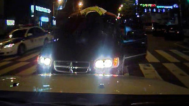 South Korean traffic cop Kim Hyun-cheol clings to the windshield of a suspect's car in Busan, South Korea, Aug. 26, 2012, in this image made from video provided by the Busan Police Agency. 