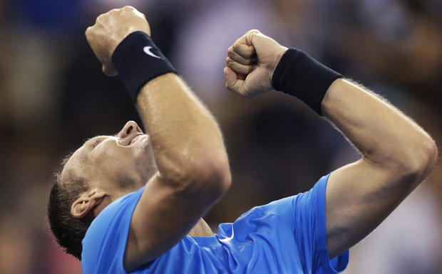 Tomas Berdych raises his arms after beating Roger Federer 