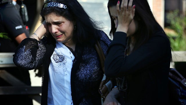 Two women who identified themselves as friends of the al-Hilli family cry as they stand at the front gate of the family's house Sept. 7, 2012, in Claygate, England. 