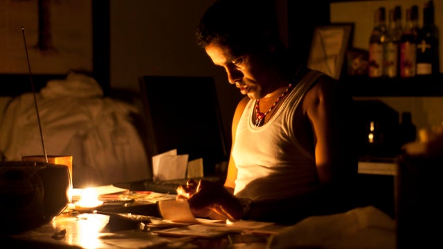 Bartender in Havan works on accounts by candlelight during blackout Sunday 