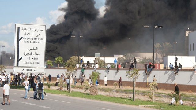 A pall of smoke rises above protesters after they set alight cars in the U.S. embassy parking lot in Tunis, Friday, Sept. 14, 2012.  
