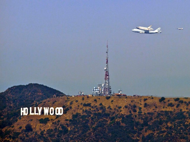 The Space Shuttle Endeavour atop a modified 747 passes the Hollywood Sign as seen from Dodger Stadium, Friday, Sept. 21, 2012, in Los Angeles, the last aerial hurrah before retiring to a Los Angeles museum. (AP Photo/Mark J. Terrill) 
