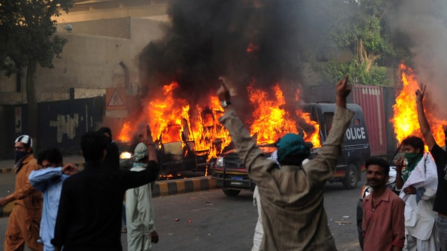 A Pakistani demonstrator throws a tear gas shell towards riot police 