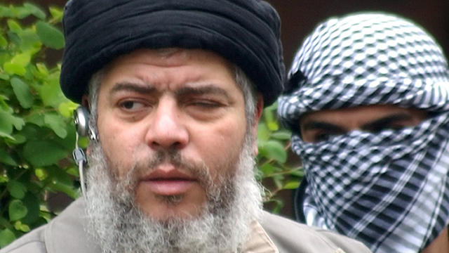 Muslim cleric Abu Hamza al-Masri, as he arrives with a masked bodyguard 