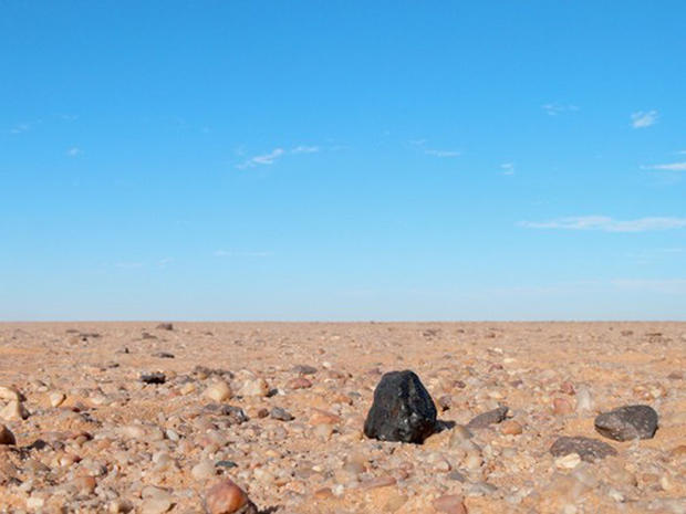 The black fragment of Almahata Sitta meteorite number 15 shows up black against the lighter coloured rocks of the Nubian desert in northern Sudan. 