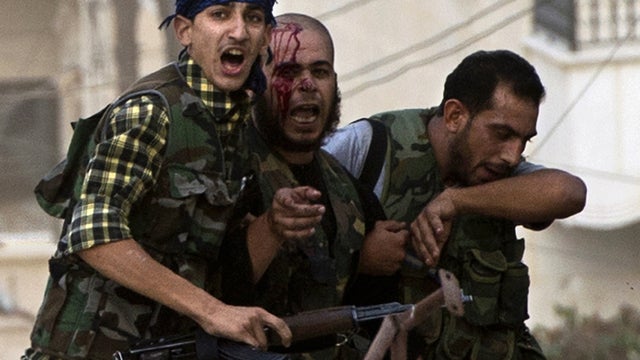 Injured rebel fighter is helped away during heavy fighting with Syrian government troops 