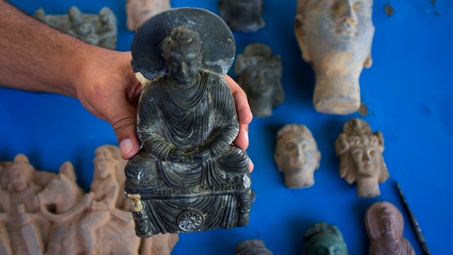 Artist Salahud Deen shows samples of reproduction Buddhist artifacts he created  