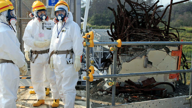 Clad in a protective outfit, Japanese Prime Minister Yoshihiko Noda, right, stands on the rooftop of the Unit 4 reactor building during his inspection of the crippled Fukushima Dai-ichi nuclear power plant in Okuma, Japan, Oct. 7, 2012. 