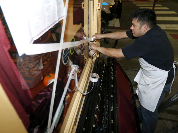 Oswaldo Falleres puts tape on the window of a restaurant in preparation for the arrival of superstorm Sandy Oct. 28, 2012, in Hoboken, N.J. 