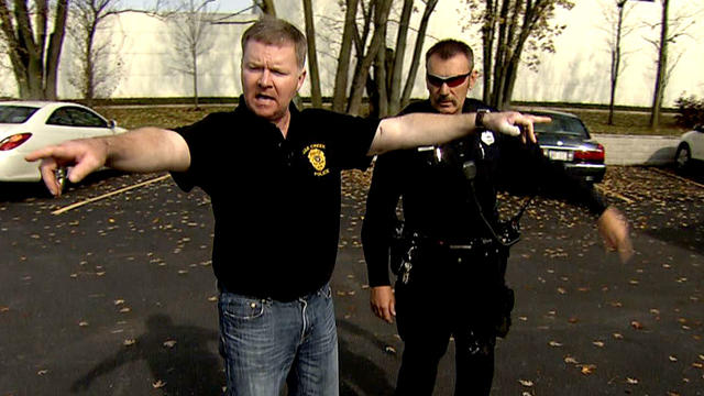 Lt. Brian Murphy, front, and Officer Sam Lenda demonstrate what happened during an August morning shootout in the parking lot of a Sikh temple in Wisconsin. Six people were killed, and Murphy was shot 12 times. 