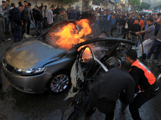 Palestinians extinguish fire from the car of Ahmaed Jaabari, head of the military wing of the Hamas movement, the Ezzedin Qassam Brigades, after it was hit by an Israeli air strike in Gaza City Nov. 14, 2012. 
