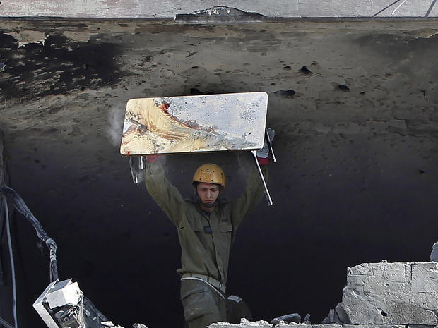 An Israeli soldier throws a blood-stained table from an apartment building hit by a rocket fired from the Gaza Strip 