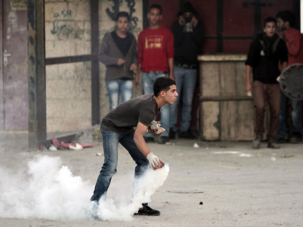 A Palestinian readies to throw back a tear gas canister fired by the Israeli military during a protest against Israel's operations in Gaza the Qalandia checkpoint, in the Israeli occupied West Bank, on November 18, 2012. 