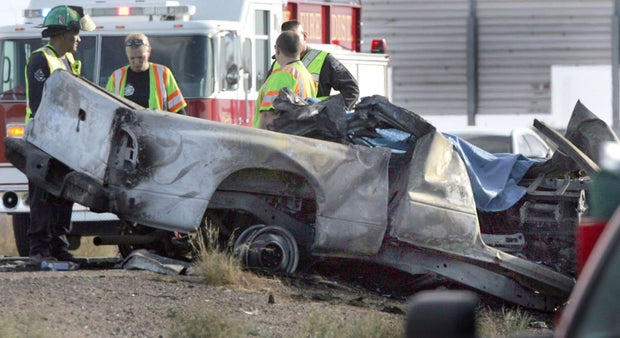 Emergency personnel are next to a burned truck that was traveling east in the the west bound lanes of Interstate 10 and struck a tour bus Tuseday Nov. 20, 2012 in Casa Grande, Ariz.