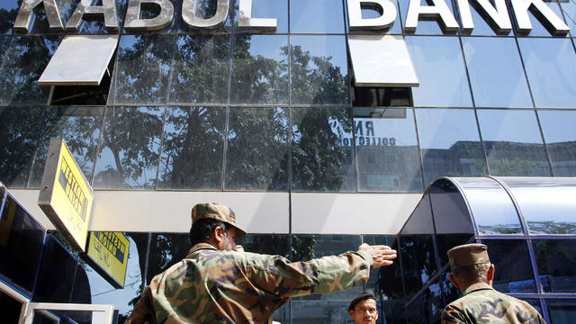 Afghan soldiers chat in front of the main office of Kabul Bank in Kabul, Afghanistan, Sept. 1, 2010. 