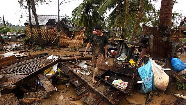 Residents walk amongst their destroyed houses after Typhoon Bopha hit Compostela town 
