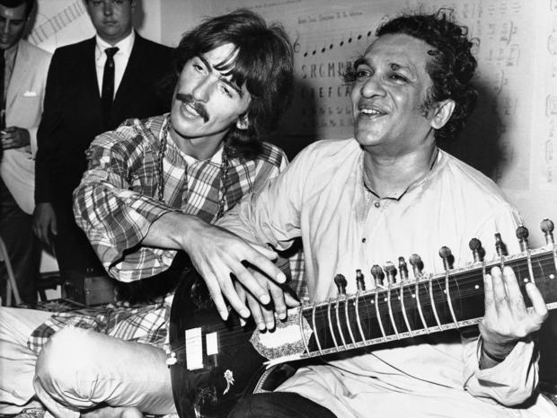 Aug. 3, 1967 file photo shows George Harrison, of the Beatles, left, sitting cross-legged with his musical mentor, Ravi Shankar, of India, in Los Angeles, as Harrison explains to newsmen that Shankar is teaching him to play the sitar 