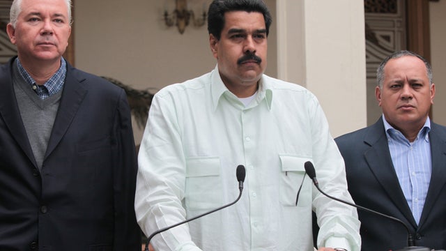 In this photo released by Miraflores Press Office, Venezuela's Vice President Nicolas Maduro, center, addresses the nation on live television flanked by Oil Minister Rafael Ramirez, left, and National Assembly President Diosdado Cabello at the Miraflores  