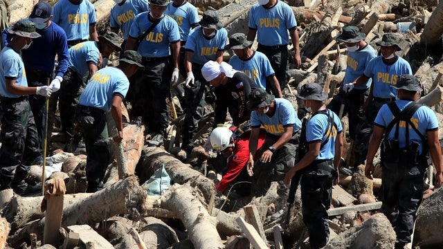 Police search around toppled tree trunks caused by the powerful Typhoon Bopha in New Bataan, Philippines, Dec. 10, 2012, in this handout picture released by the Philippine National Police. 