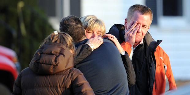 Unidentified people react on December 14, 2012 at the aftermath of a school shooting at a Connecticut elementary school that brought police swarming into the leafy neighborhood, while other area schools were put under lock-down, police and local media said. Local media quoted that the gunman had died at the Sandy Hook Elementary School in Newtown, Connecticut, northeast of New York City. At least 27 people, including 18 children, were killed on Friday when at least one shooter opened fire at an elementary school in Newtown, Connecticut, CBS News reported, citing unnamed officials. 