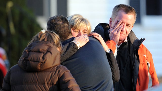 Unidentified people react on December 14, 2012 at the aftermath of a school shooting at a Connecticut elementary school that brought police swarming into the leafy neighborhood, while other area schools were put under lock-down, police and local media sai 