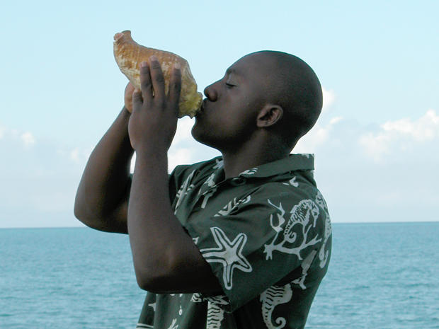 Man blowing conch shell 