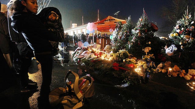 Isabel Lebron holds son Izaiah Taylor at a memorial with donated Christmas trees honoring victims near the school on the first Sunday following the mass shooting at Sandy Hook Elementary School on December 16, 2012 in Newtown, Conn.  