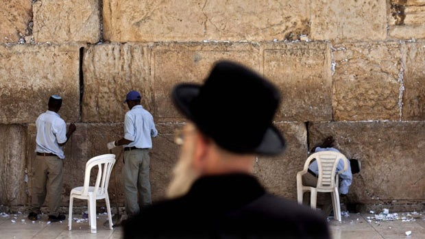 an ultra-Orthodox Jewish man stands as Israeli workers remove prayer notes left by visitors from between the stones of the Western Wall, the holiest site where Jews can pray, in Jerusalem's Old City. 