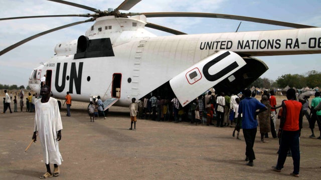 People who fled ethnic violence in South Sudan's Jonglei state line up at the rear of a helicopter for the arrival of food from the U.N.'s World Food Programme in Pibor, South Sudan, Jan. 12, 2012. 