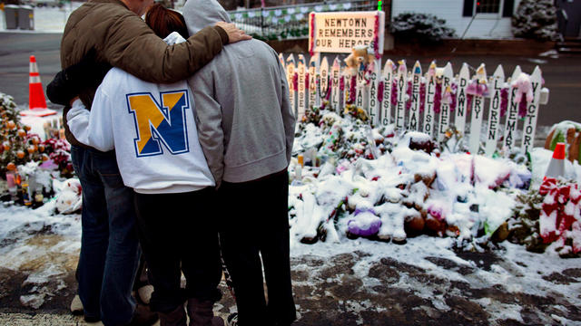 Members of the Rutter family of Sandy Hook, Conn., embrace early Christmas morning as they stand near memorials by the Sandy Hook firehouse in Newtown, Conn.,Tuesday, Dec. 25, 2012. People continue to visit memorials after gunman Adam Lanza walked into Sa 