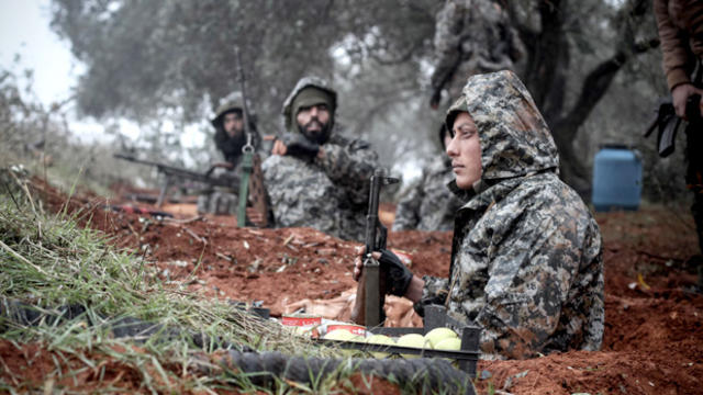 In this Sunday Jan. 6, 2013 photo Syrian rebel fighters take their positions in foxholes on the frontline of the ongoing battle for the military airport in Taftanaz, Syria. 