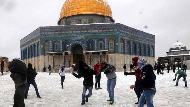 People play in the snow in front of the Dome of the Rock 