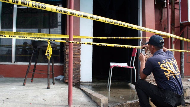 A Philippine National Police investigator takes photos of Drysden Hotel which caught fire early Friday, Jan. 11, 2013 at Olongapo city, a former U.S. naval base, west of Manila, Philippines. The fire swept through the hotel in a Philippine resort city ear 