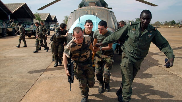 Malian soldiers helped by French troops move a broken helicopter out of a hangar to make room for more incoming troops at the airport in Bamako, Mali, Jan. 15. 2013. 