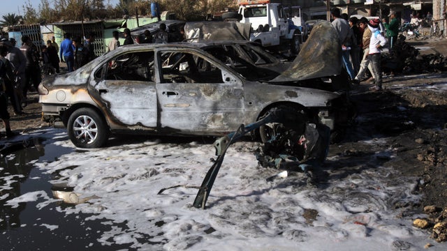 People gather around the site of a car bombing in the north Baghdad neighborhood of Shuala Jan. 22, 2013. 