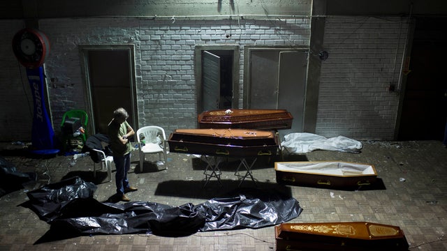 A man stands around coffins containing the remains of victims after the bodies were identified at a gymnasium in Santa Maria city, Rio Grande do Sul state, Brazil, Sunday, Jan. 27, 2013. A fast-moving fire roared through the crowded, windowless Kiss night 