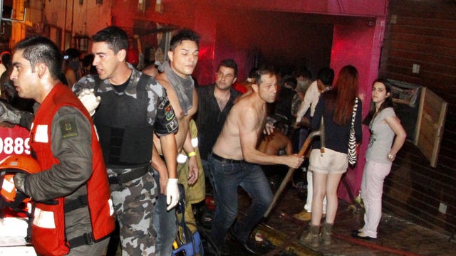 People escape the Kiss nightclub in Santa Maria, Brazil, as a fire burns inside 