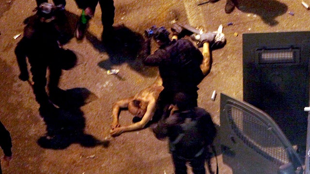 Egyptian riot police beat a man, after stripping him, and before dragging him into a police van, during clashes next to the presidential palace in Cairo, Egypt, Friday, Feb. 1, 2013. Protesters denouncing Egypt's Islamist president hurled stones and fireb 