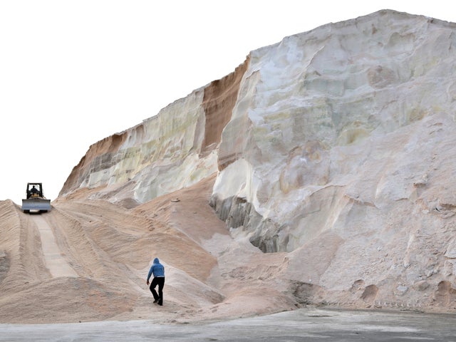 A worker walks up toward a plow smoothing a large salt pile at Eastern Salt Company in Chelsea, Mass., Feb. 7, 2013, in preparation for a major winter storm headed toward the Northeast. 