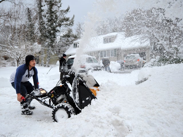 Eguin Belasquez steers a snowblower through mounds of snow as he helps his friend dig out of his driveway after a snow storm Feb. 9, 2013, in Sea Cliff, N.Y. 