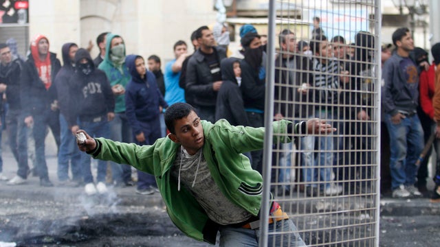A Palestinian man throws a stone towards Israeli soldiers after the funeral of Arafat Jaradat in the West Bank of Hebron, Monday, Feb. 25, 2013. Thousands have attended the funeral procession of a 30-year-old Palestinian man who died under disputed circum 