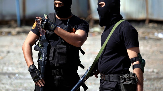 Two Egyptian police officers wear masks as they stand guard during clashes with protesters, not seen, near the state security building in Port Said, Egypt, March 6, 2013. 