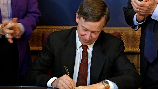 Colorado Gov. John Hickenlooper is applauded by lawmakers as he signs the state's gun control bill into law at the Capitol in Denver on March 20, 2013.  